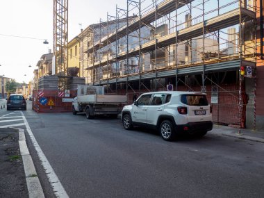 Cremona, İtalya 6 Ağustos 2025 Beyaz Jeep Renegade inşaat iskelesi, vinç ve kamyonla bir inşaat sahasının yakınındaki bir caddeye park etmiş, kentsel gelişim ve faaliyet sahnesi yaratıyor.