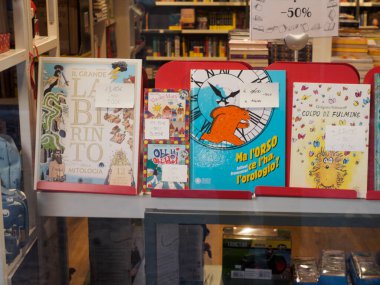 Cremona, İtalya 6 Ağustos 2025 İtalyan çocuk kitapları Cremona, Lombardy, İtalya 'da bir kitapçının vitrininde sergileniyor ve indirim etiketleri yüzde 50 indirimli.