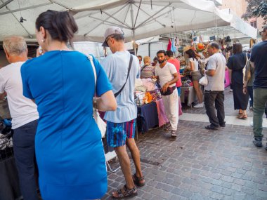 Cremona, İtalya 6 Ağustos 2025 canlı tezgahlarda gezen ve alışveriş yapan turistler güneşli bir yaz gününde Cremona, İtalya 'da canlı bir açık hava pazarında giysi ve çanta satıyorlar.