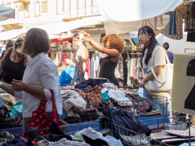 Cremona, İtalya - 6 Ağustos 2025 Lombardiya 'daki canlı sokak piyasa sahneleri çeşitli giyim mağazaları ve alışveriş merkezlerinin etkileşimi güneşli gökyüzünün altında canlı bir atmosfer yaratıyor