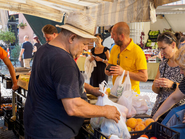 Cremona, Italy - August 6th 2025 Vibrant Italian Street Market Scene Featuring Shoppers Selecting Fresh Produce and Local Goods Under a Sunny Sky in Lombardy Italy