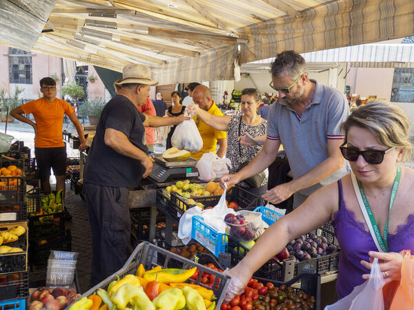 Cremona, Italy August 6th 2025 People buying fresh produce from local vendors at a lively outdoor market in Cremona, Lombardy, Italy, enjoying ripe selections