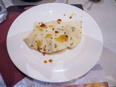Crispy Lentil Papadum Indian Appetizer Drizzled with Savory Spiced Oil Served on a White Plate Ready to Be Enjoyed as a Delicious Snack