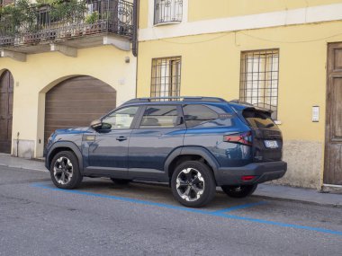 Cremona, İtalya - 28 Temmuz 2025 Modern Dark Blue Dacia Bigster SUV Eski Sarı Bina Cephesi Windows ve bir Archway ile Avrupa 'da bir kaldırım taşı caddesinde park etti
