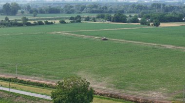 Uçsuz bucaksız bir soya tarlasında traktör kullanan bir çiftçinin hava perspektifi ticari imaj lisansı için gelişmiş tarım yöntemlerini sembolize eden temel ürün koruma tedavilerini uyguluyor.