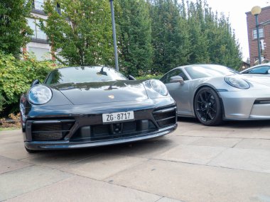 Cremona, İtalya 22 Ağustos 2025 siyah bir Porsche 911 'in ön görüntüsü gümüş renkli bir Porsche' nin yanında şehir ortamında, lüks ve otomotiv tasarımı sergileniyor.