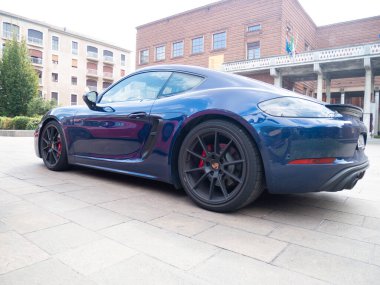 Cremona, İtalya 22 Ağustos 2025 Koyu mavi Porsche 718 Cayman tarihi bir binanın önündeki bir meydanda park halinde.