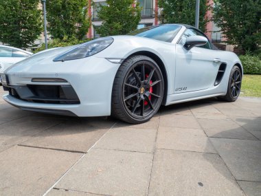 Cremona, İtalya 22 Ağustos 2025 Beyaz bir Porsche 718 Boxster GTS 4.0 'ın asfalt bir alana park edilmiş görüntüsü, şehir ortamında spor tasarımı ve lüks özelliklerini sergiliyor.