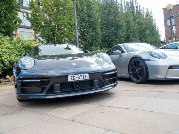 Cremona, İtalya 22 Ağustos 2025 siyah bir Porsche 911 'in ön görüntüsü gümüş renkli bir Porsche' nin yanında şehir ortamında, lüks ve otomotiv tasarımı sergileniyor.