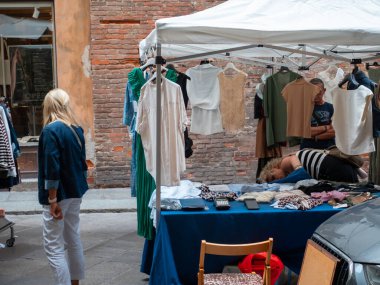 Cremona, Italya- 23 Ağustos 2025 Bir İtalyan Şehir Meydanı 'nda Açık Hava Kıyafet Dükkanı Tarihi Mimarlık ve Sıcak Güneş Işığı Ortasında Alışverişçiler için Moda Giysileri