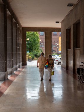 Cremona, İtalya 22 Ağustos 2025 'te Cremona Caddesi' ndeki bir markette el ele yürüyen yaşlı bir çift, alışveriş torbaları taşıyorlar.