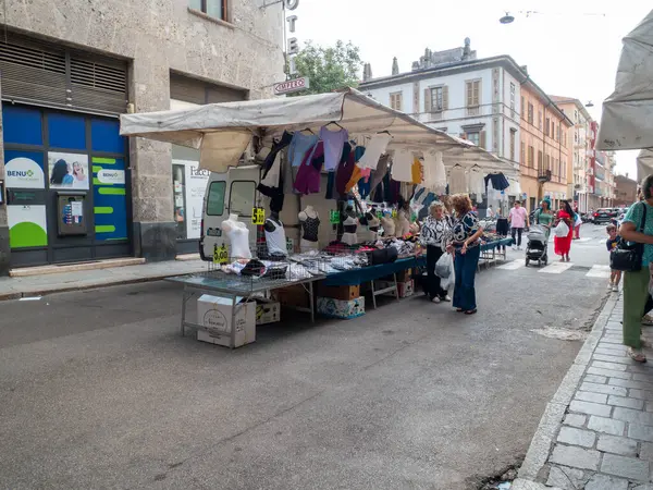 Cremona, Italy- 23 Ağustos 2025 Cremona Lombardy İtalya 'da bir kaldırım taşı caddesinde giysi ve eşya satan çeşitli tezgahlarla hareketli bir açık hava pazarı.