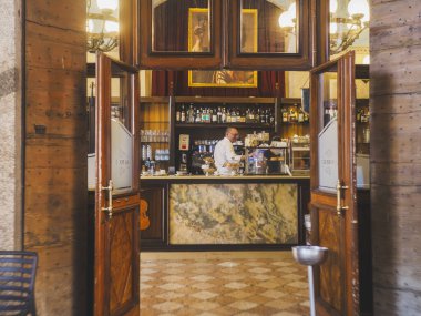 Cremona, İtalya - 3 Temmuz 2025 Tarihi İtalyan barı içi mermer tezgahlı ve kahveci açık ahşap kapılardan görülebilen içecekleri şehir meydanında hazırlıyor