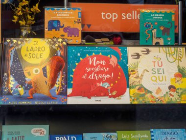 Milan, İtalya 14 Ağustos 2025 Milan, İtalya 'da bir kitapçının penceresini dolduran renkli çocuk kitapları, Il Ladro di Sole ve Non Svegliare il Drago gibi ilgi çekici başlıklar içeriyor.