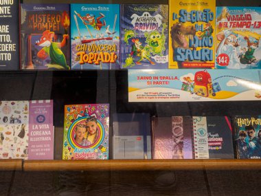 Milan, İtalya 14 Ağustos 2025 Renkli Çocuk Kitapları. Geronimo Stilton ve Harry Potter serileri de dahil. Milano 'daki bir kitapçıda ahşap bir rafta.