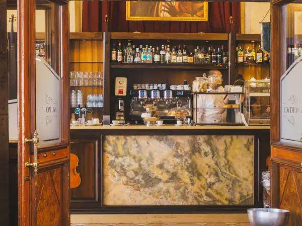 Cremona, İtalya - 3 Temmuz 2025 Klasik bir İtalyan kafe barının içinde ahşap kapılar açık mermer tezgah espresso makineleri içki şişeleri ve cam bardakların atmosferini yansıtıyor.