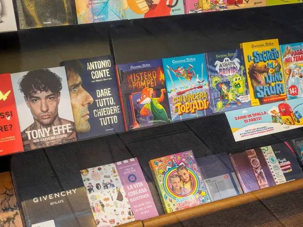 Milan, İtalya 14 Ağustos 2025 Romanlar, çocuk kitapları, biyografiler ve moda başlıkları içeren renkli edebiyat türleri Milano, İtalya 'daki kitapçı vitrininde güzelce sergilendi.