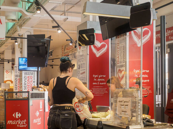 Кремона, Италия - 14 августа 2025 года Потребитель покупает крупы на прилавке в современном интерьере дисконтного супермаркета во время типичного дня шопинга