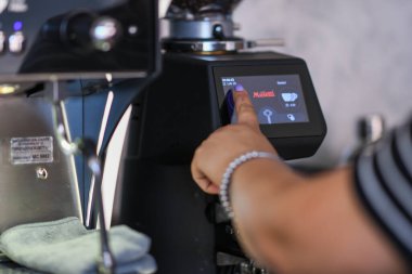 Cremona, İtalya - 19 Temmuz 2025 Kahve makinesinin dijital ekranında bir kahve makinesinin düğmesine basarak bir baristanın elini kapatın