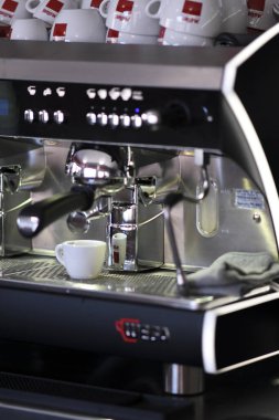 Cremona, İtalya 19 Temmuz 2025 Paslanmaz çelik espresso makinesi zengin kahve ve Musetti fincanları hazırlıyor, çağdaş kafe ortamında profesyonel barista çalışma alanını vurguluyor.