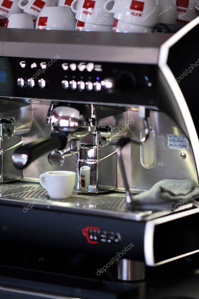 Cremona, Italy July 19th 2025 Stainless steel espresso machine preparing rich coffee, Musetti cups lined up behind, highlighting professional barista workspace in contemporary cafe setting