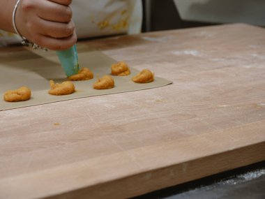 Genç bir kadının becerikli ellerini dikkatlice makarna hamuru çarşaflarına doldurup profesyonel bir mutfak ortamında geleneksel İtalyan dolgulu tortelli yapmaya hazırlanıyor.