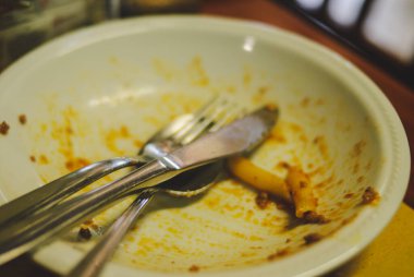 İtalya 'nın Cremona şehrindeki bir masada arta kalan makarna sosu ve çatal bıçaklarla dolu kirli bir kasenin yakın çekimi leziz bir İtalyan yemeğinin kalıntılarını sergiliyor.