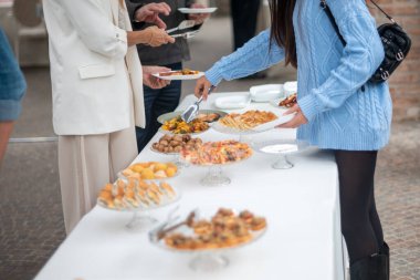 People enjoying a lavish buffet spread at an elegant private event with various delicious food options being served