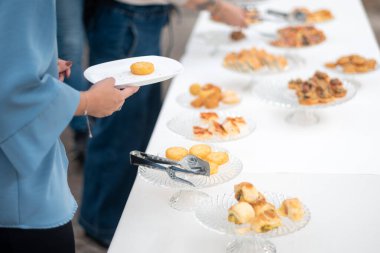 Guests enjoy an elegant private event buffet selection of gourmet appetizers and finger foods served on a long white table during a social gathering