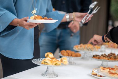 Elegant guests gather around a beautifully arranged buffet table selecting delicious appetizers and savory dishes at a sophisticated private event celebration