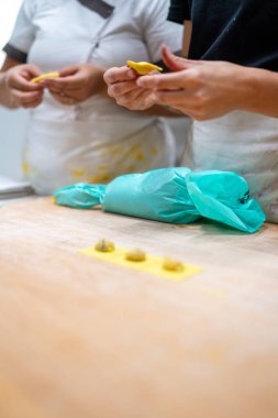 Two people are making ravioli pasta by hand in a close up detailed shot showing the process of creating Italian food