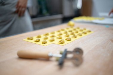 Expertly crafted fresh handmade ravioli pasta filling dough arranged meticulously on a yellow mold ready for cooking