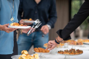 People gathering around a buffet table selecting small appetizers and finger foods during an informal social event celebration