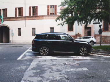 Cremona, Italy - October 1st 2025 Black MINI Countryman SUV parked on an old city street next to a building, embodying urban mobility and modern automotive style