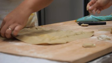 Passionate chef meticulously crafting delicate fresh pasta dough by hand in a small authentic Italian restaurant kitchen focusing on traditional culinary artistry