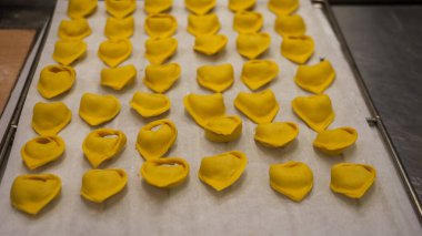 Hands Crafting Heart Shaped Pumpkin Stuffed Ravioli with Intense Focus in a Cozy Italian Kitchen for Autumnal Delight