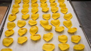 Artisan Chefs Meticulously Crafting Handmade Pumpkin Stuffed Ravioli for Autumn Feast with Intense Focus in a Cozy Small Business Kitchen