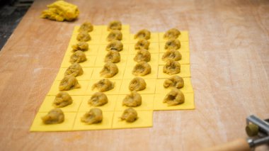 Close up professional kitchen scene of fresh homemade pumpkin stuffed ravioli being prepared with passion and focus for fall season Italian cuisine in a small business setting
