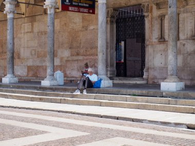 Cremona, Italy - September 18th Elderly Gentleman Enjoying a Peaceful Moment Sitting on Ancient Stone Steps Outside Historic Building in Lombardy Italy on a Sunny Day