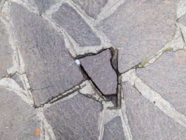 Close up view of cracked cobblestone pathway texture showing wear and tear with a small piece of debris visible in the damaged area a perfect representation of urban decay and the passage of time in a historic European city street scene