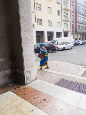 Cremona, Italy - September 18th 2025 Woman in Traditional Clothing Walking Down Stairs in a European City Square with Cars Parked on the Street Behind Her