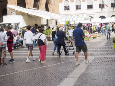 Cremona, Italy - September 18th 2025 Bustling Open Air Market Scene in a Historic Italian City Square on a Sunny Day Featuring Diverse Shoppers and Colorful Flower Stalls
