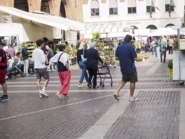 Cremona, Italy September 16th 2025 Varied crowd strolls and browses a sunny outdoor market in Cremona, Italy, with vendors selling plants and goods in a lively town square during daytime leisure and