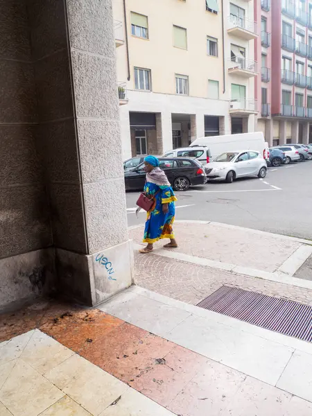 Cremona, Italy - September 18th 2025 Woman in Traditional Clothing Walking Down Stairs in a European City Square with Cars Parked on the Street Behind Her