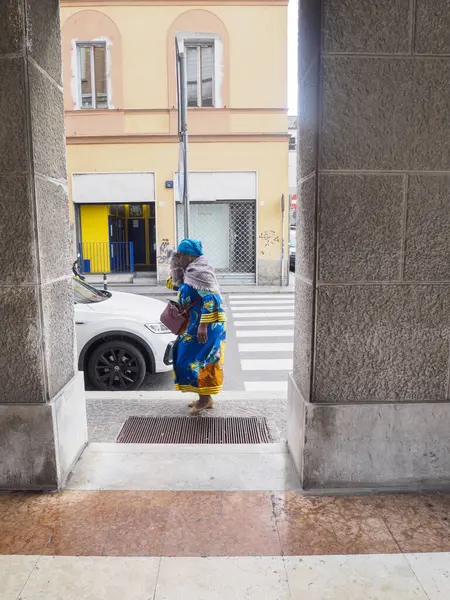 Cremona, Italy - September 18th 2025 Elegant woman in traditional colorful attire crosses a pedestrian street in a European city with modern architecture and shops creating a vibrant street scene