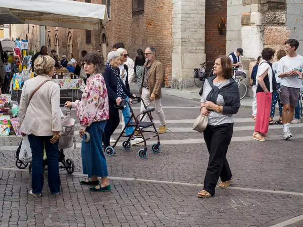 Cremona, Italy September 16th 2025 Diverse group of people, including adults, mature adults, and senior adults, walking and shopping at a vibrant street market on a cobblestone street