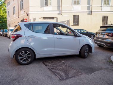Cremona, İtalya - 28 Temmuz 2025 Modern Light Gray Hatchback Gündüz vakti Şehir Arkaplan Taşımacılığında Binaları olan bir kaldırım taşı caddesine park etti