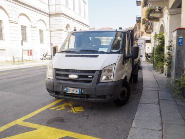 Cremona, İtalya 29 Temmuz 2025 Beyaz Ford Transit minibüsü güneşli bir günde, İtalya 'nın Torino kentindeki bir caddede yükleme ve boşaltma alanında, engelli park alanında yasadışı park edilmiş.