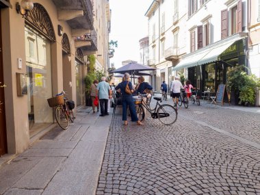 Cremona, İtalya - 28 Temmuz 2025 Sunny European City Street Scene with People and Biicycles Tjoying Outdoor Cafes and Cobblestone Pavement on a Ilık Öğleden Sonra