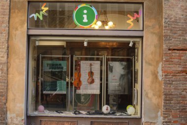 Cremona, Italy - September 22nd 2025 Storefront window of a tourist information point in Cremona, Italy, displaying violins and posters for music and opera